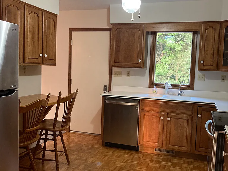 Kitchen featuring stainless steel appliances, corian countertops, parquet wood flooring, and bar for 2.