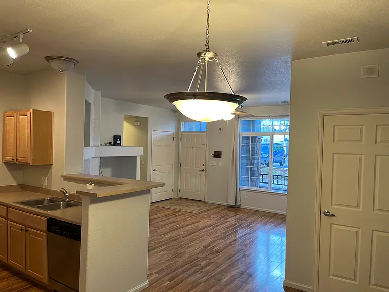 Kitchen view facing living room and front door. Additional storage room shown on right.