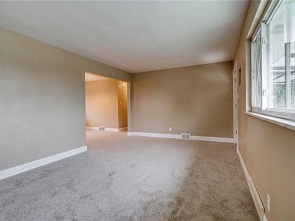 Large living room with new neutral carpet, base boards and paint. Hard wood floors are beneath the carpet.