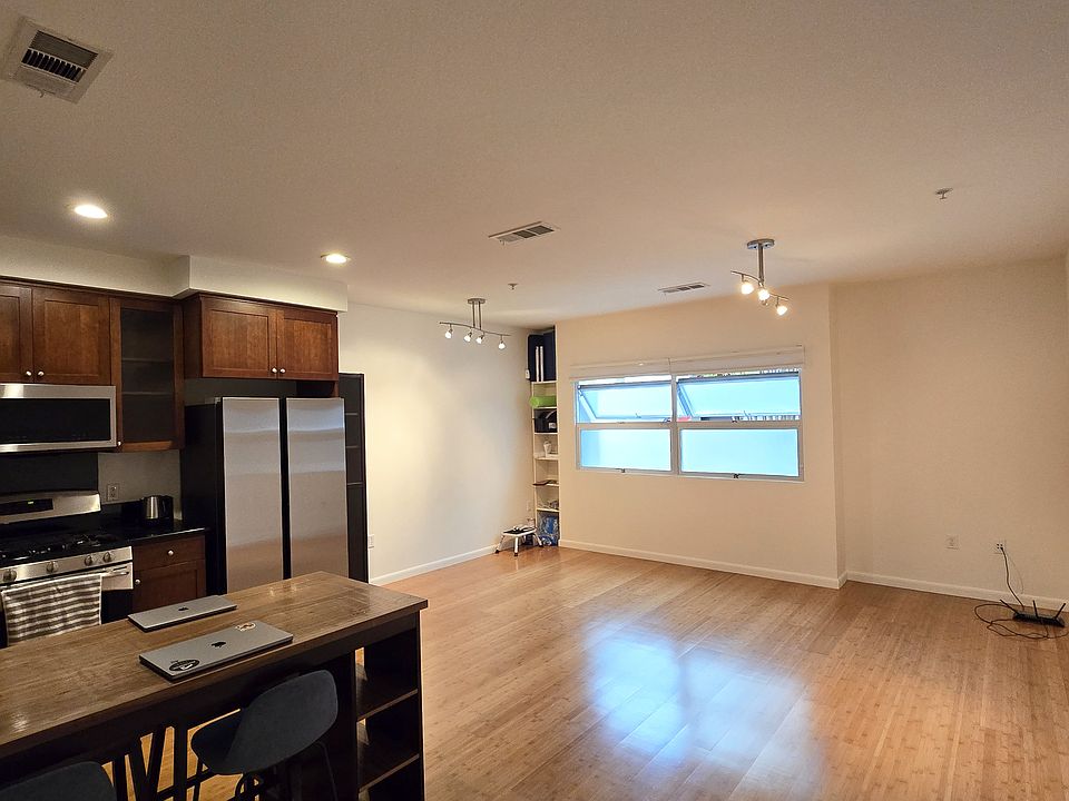 Living area with updated appliances and dining table w/ stools.