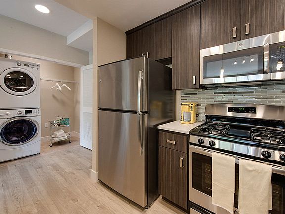 Kitchen with stainless steel appliances and closet with washer and dryer.
