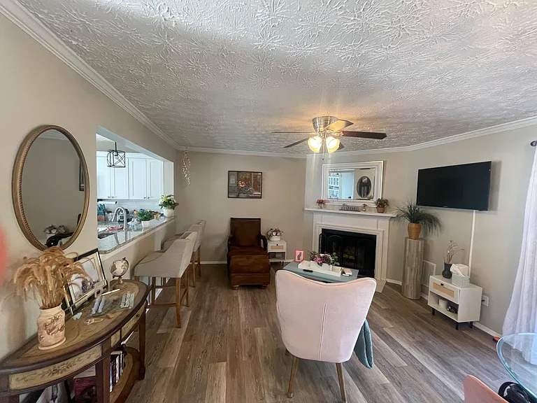 Open living area with fireplace, mounted TV, and durable flooring, flowing into a breakfast bar overlooking the kitchen.