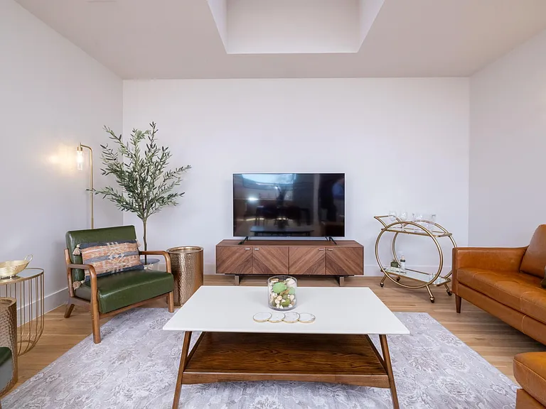 Inviting living room with a comfy couch, two chairs, flat-screen TV, and a stylish bar cart_perfect for relaxing or entertaining.