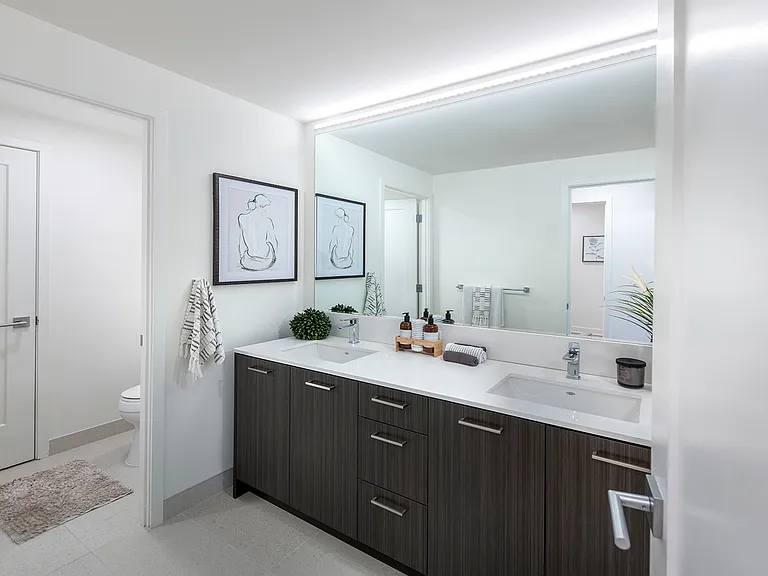 Bright bathrooms with backlit bathroom mirrors, walk-in showers, and double vanities in select homes