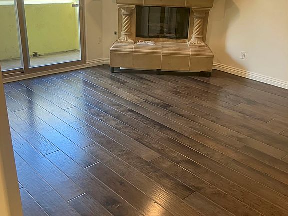 Entry into the great room with fireplace. Small balcony patio accessible through the sliding glass door.