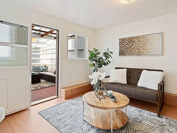 Bright, sunny living room area next to bedroom and off of the kitchen area. Door leads to shared covered sunroom (bonus room for entertainment)
