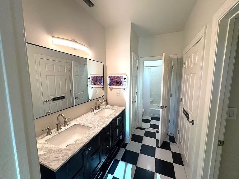 Bathroom with double sinks, linen closet, and stacked washer and dryer