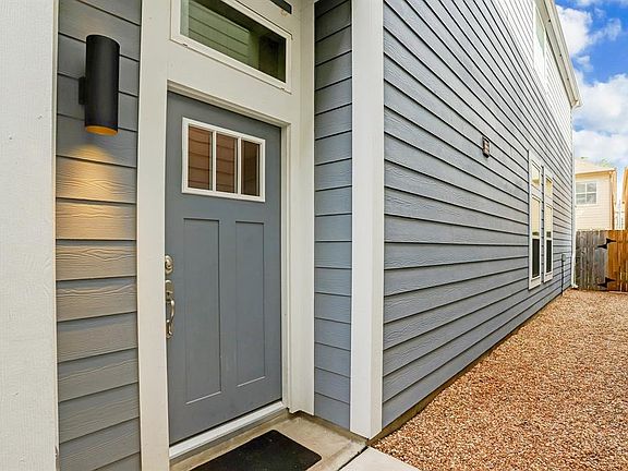The front door is tucked around the side of the home beyond a wrought-iron gate.
