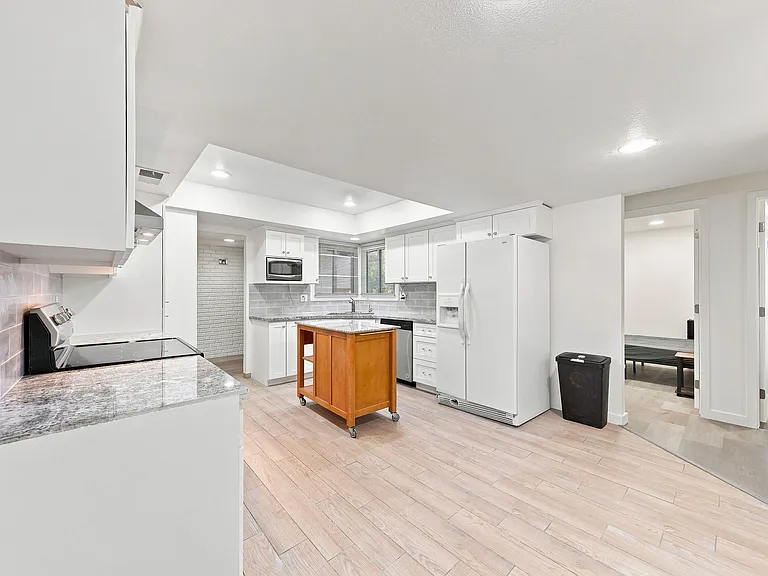 Spacious kitchen with ample white cabinetry, granite-look counters, movable island, and full appliance suite.