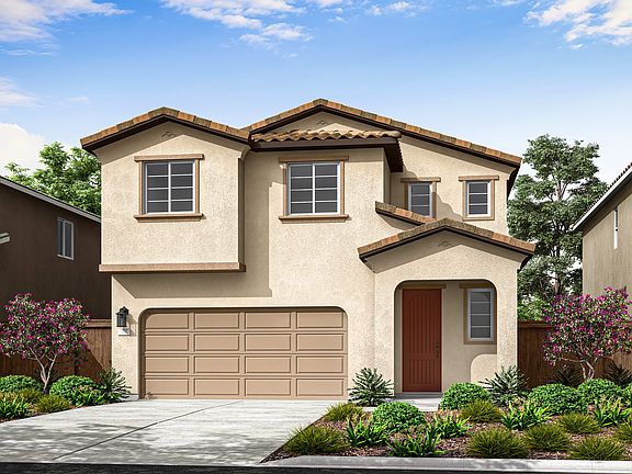 A two-story stucco house with a red tile roof, surrounded by lush landscaping and a paved driveway l