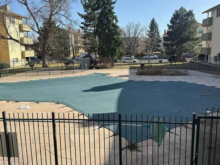 The community swimming pool is right next to the entry door of an apartment.