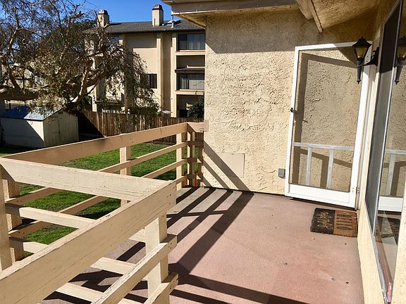 The actual unit does not have a screen door and there is an apartment building next door, not a house back yard.