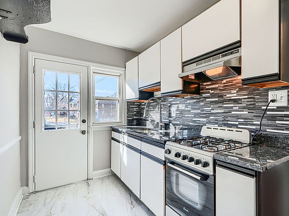 Freshly renovated kitchen with under-cabinet lighting, new granite countertops, flooring, a new stove, and freshly painted cabinets.