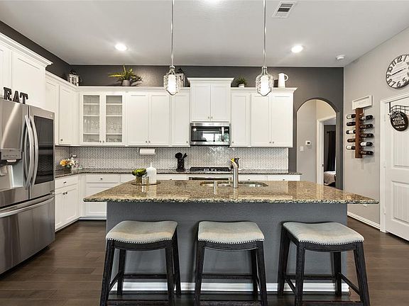 This spacious kitchen features white cabinets, SS appliances, recessed lighting, and granite kitchen island!