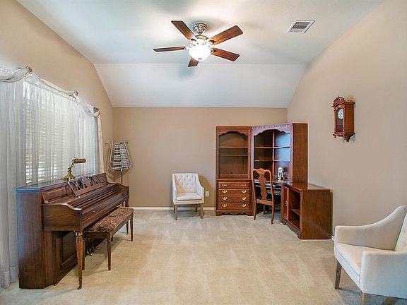 Formal living room just off the entry features plush carpet and ceiling fan.