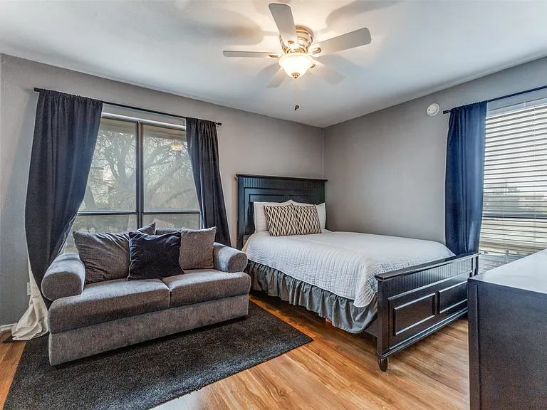 Interior room featuring wood-finish flooring, two large windows, and a ceiling fan with integrated lighting