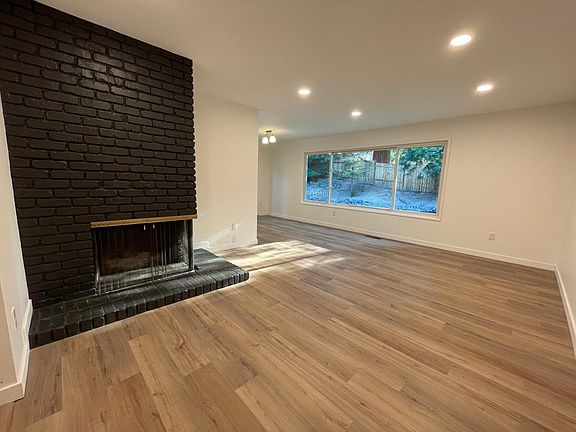 Spacious living room with fireplace, dimmable lighting, and large windows with natural light