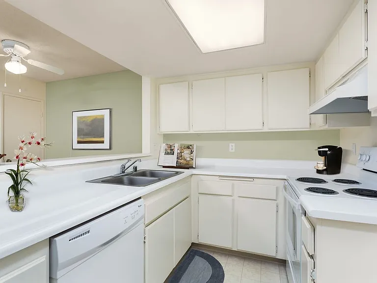 Classic Package kitchen with white appliances, white laminate countertops, white cabinetry, and vinyl flooring
