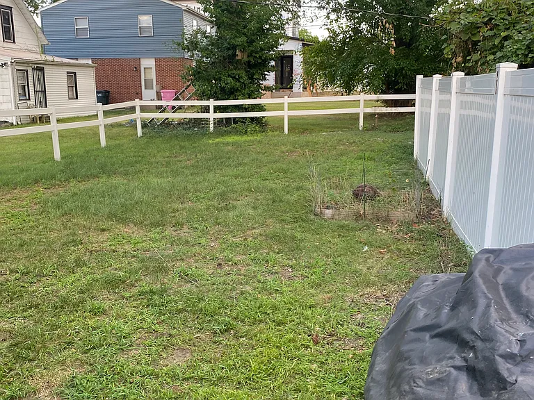 Fenced back yard with propane grill covered in front