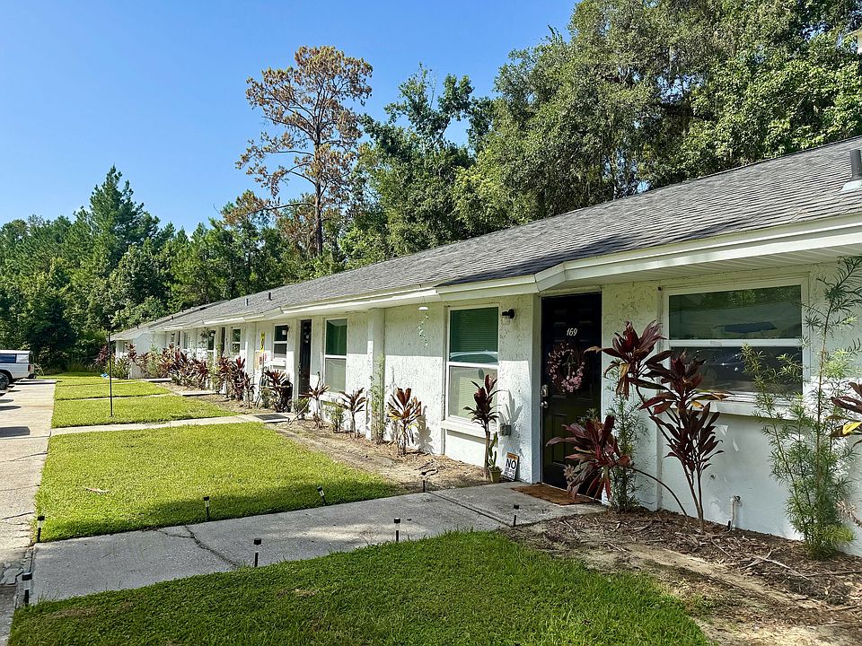 Charming row of single-story homes with lush greenery and modern landscaping in a serene neighborhood setting.