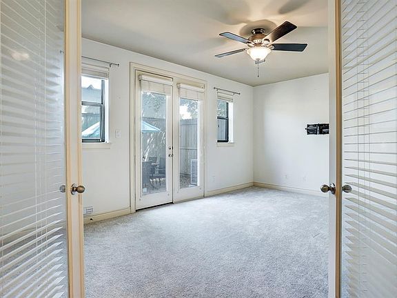 Enter the first floor bedroom via glass French doors. It can be also used as an office or television room. It has a ceiling fan, walk-in closet, an en-suite bathroom, and access to the backyard patio.