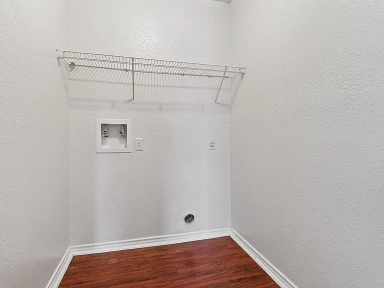 Spacious utility room with elegant wood-style flooring and shelving, ideal for laundry or storage needs. Spacious utility room with elegant wood-style flooring and shelving, ideal for laundry or storage needs.