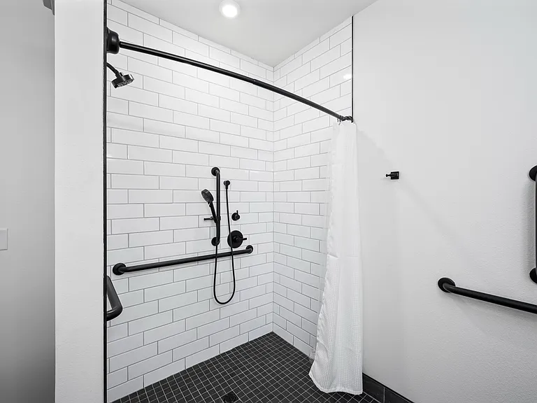Modern bathroom with sleek white subway tiles, elegant black fixtures, and an accessible design featuring grip bars. Modern bathroom with sleek white subway tiles, elegant black fixtures, and an accessible design featuring grip bars.