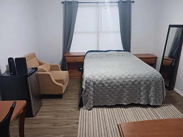 Master bedroom, queen bed, facing east, mini-fridge, lounge chair, with private bathroom and closet.