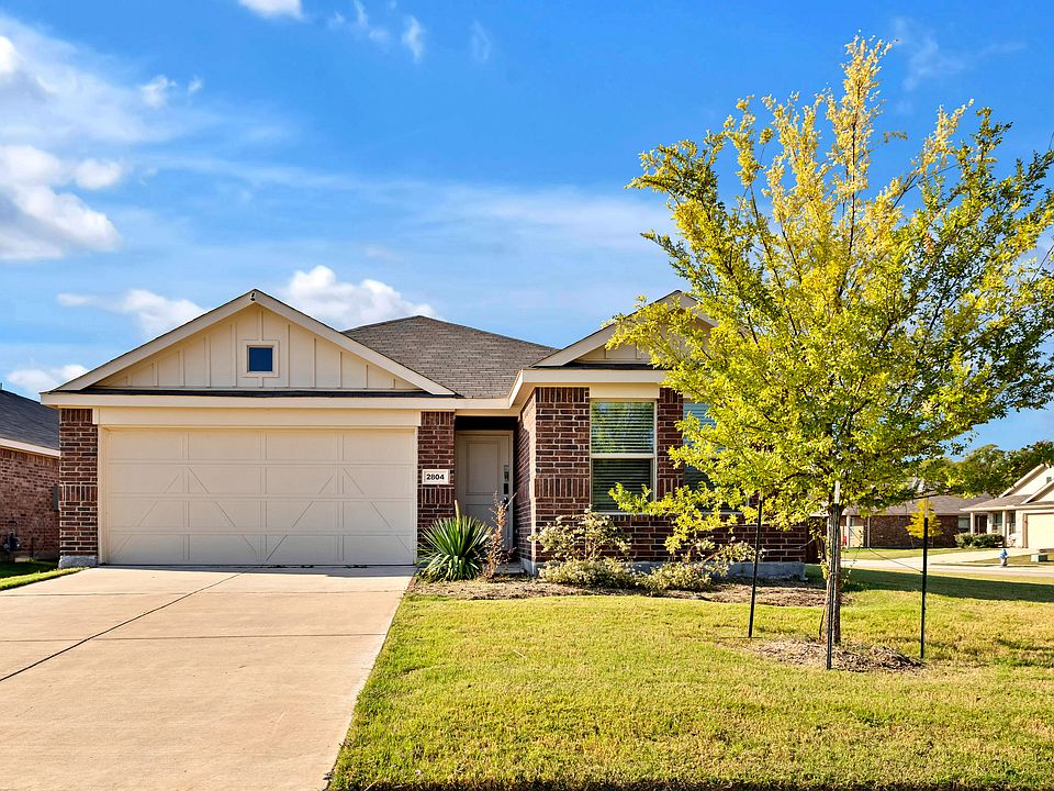 Ranch-style house featuring an attached garage, brick siding, and driveway