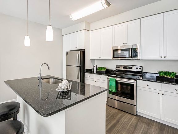 Kitchen with granite countertops, white shaker cabinetry, stainless steel appliances, kitchen island and hard surface flooring