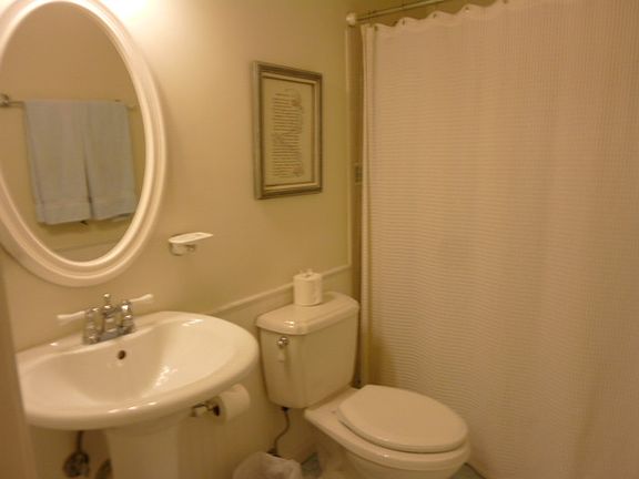 The hall bath is so cute, with sea blue glass floor tile, also accented in shower, pedestal sink, and wainscotting.