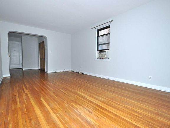 Large Corner Living Room with Hardwood floors opens to the dining foyer and overlooking Tree Lined Garth Road. The living room is 19'-10" x 12'-2".