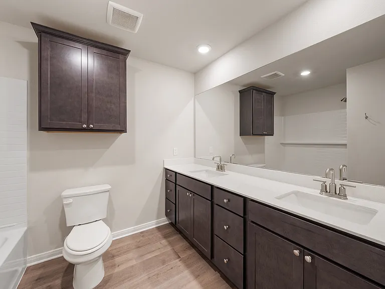 The secondary bathroom has a dual-sink vanity and shower-tub combo.