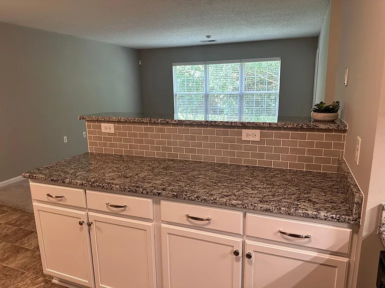 Kitchen Looking into Living Room w/ Countertop and Bar