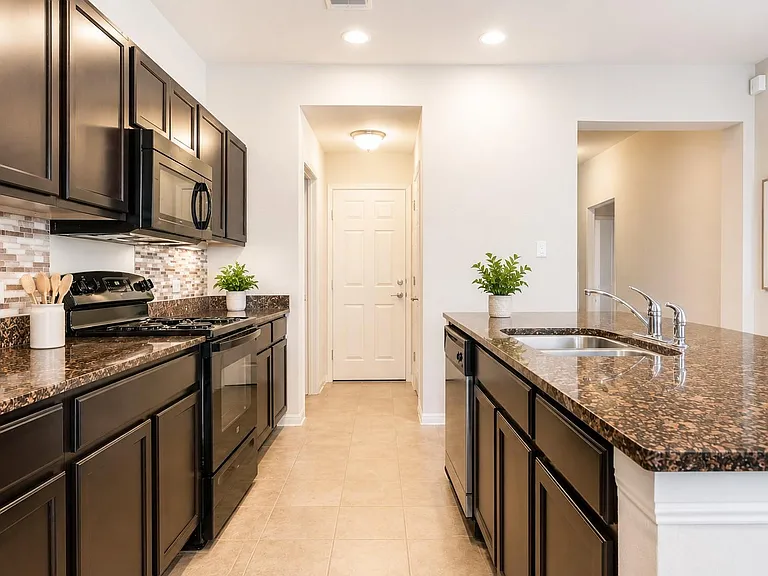 Spacious kitchen with ample dark cabinetry, stone-look counters, gas range, and a breakfast bar with double sink.