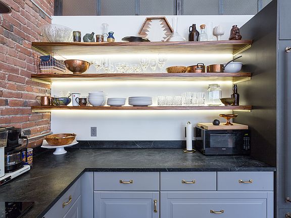 LED lit zebra wood open shelving, soapstone countertops, glass electric stove, oversized fridge.
