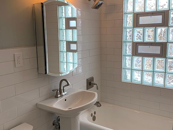 Completely renovated bathroom with subway tile backsplash and pedestal sink