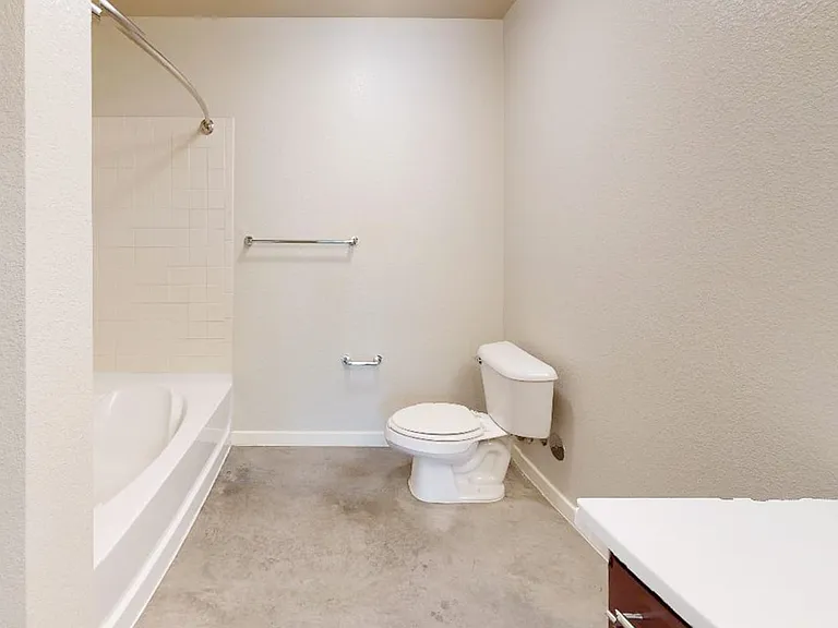 Apartment bathroom with polished concrete flooring.