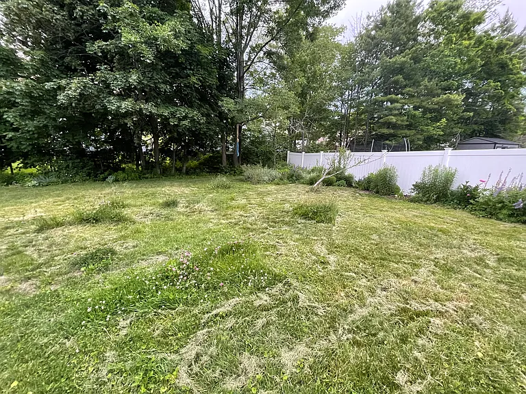 Backyard with flower gardens bordering fence.