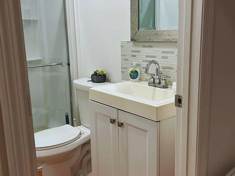 Well-appointed bathroom equipped with a toilet, shower, mirror, and storage cabinet.