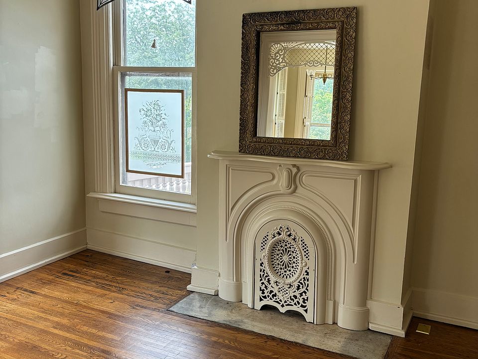 Large living room with period oak floor, original fireplace, antique stained glass