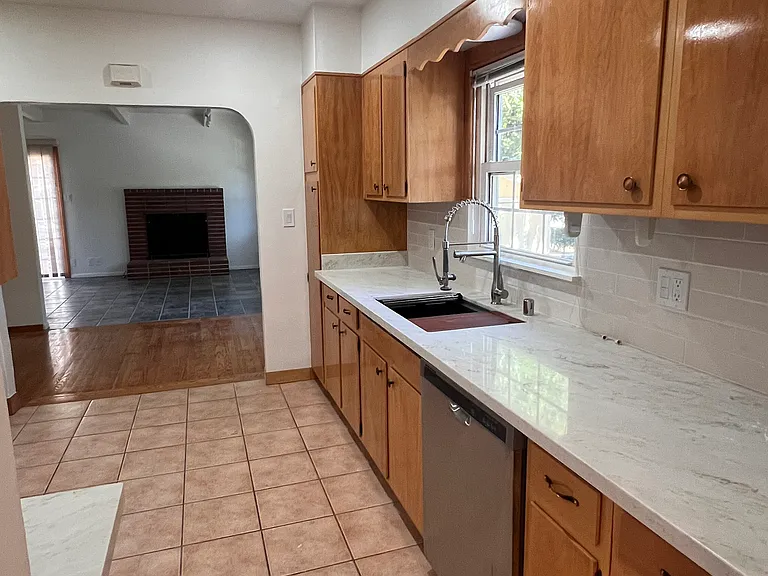 Brand new kitchen with new quartz countertops and backsplash, new gas range and exhaust fan, new kitchen sink and faucet, and a new disposal. Fridge and dishwasher also present.