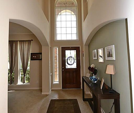 Entry offering a beveled glass front door, tile floors, two story high ceilings, door to the garage and access to a half bath.