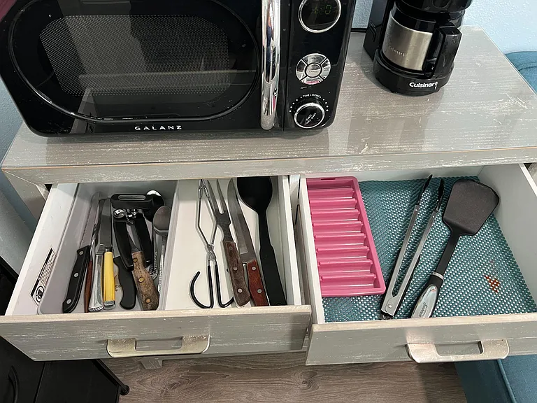 Cabinet contains basic cookware and utensels organized utensil drawers for convenient everyday cooking.