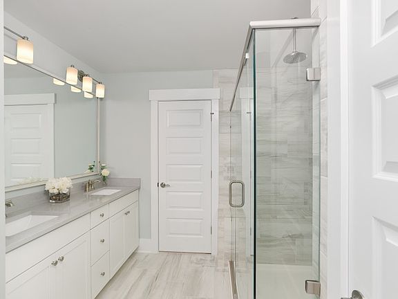 Owner s suite bath with oversized walk-in tile shower equipped with dual shower heads and bench, spa