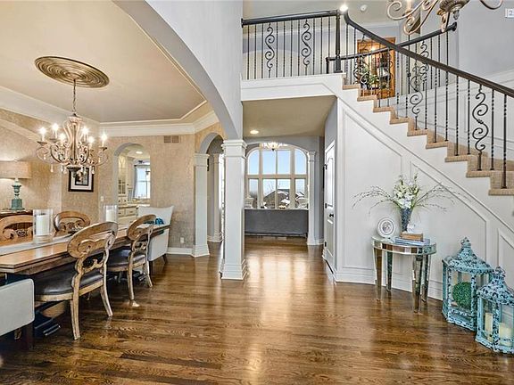 CURVED STAIRCASE OPENS TO DINING, GREAT ROOM, AND A GLIMPSE OF THE STUNNING VIEWS OF THIS SPECIAL SETTING