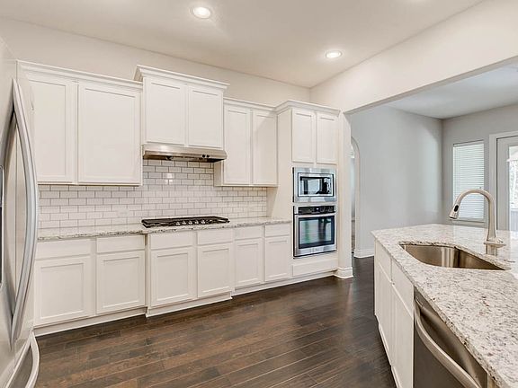 The rich, wooden floors standout next to the pristine white countertops and cabinetry.