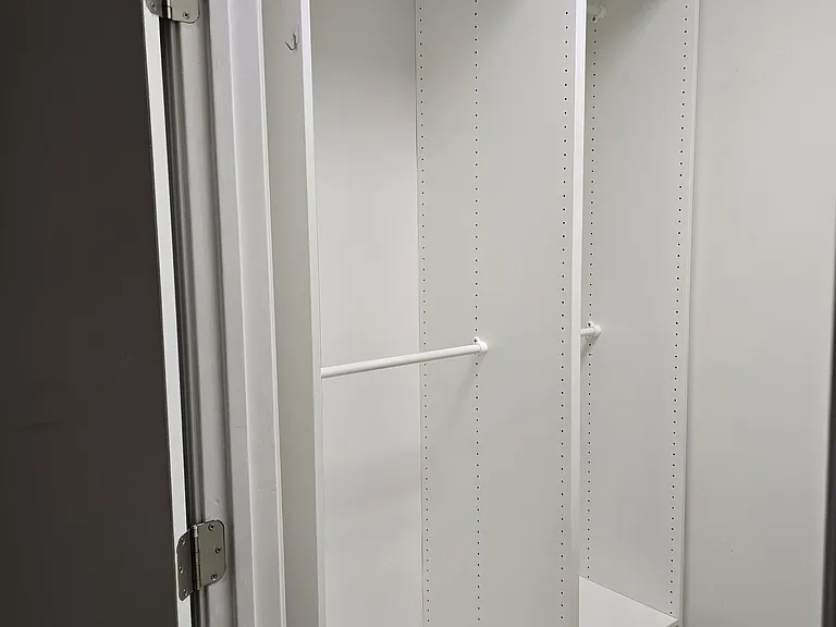 Left side of walk-in closet from bedroom; two places to hang clothes, shelves above and drawer below.