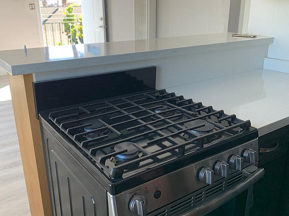 Gas stove in the kitchen overseeing living room space