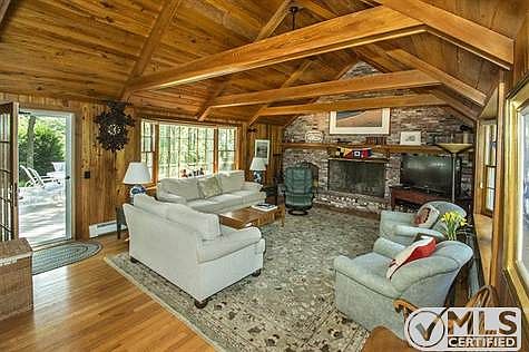 Living room with large fireplace and Cypress wood opens to patio